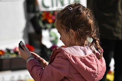 Small child in a pink jacket holding a smartphone